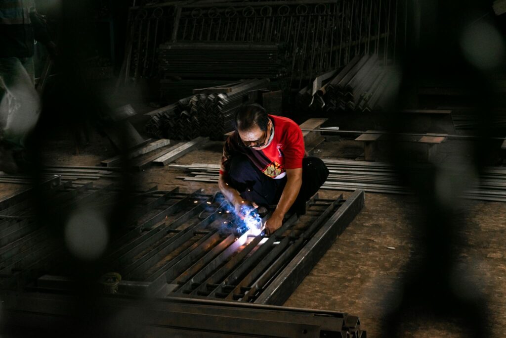 A focused welder in a workshop, working with steel and sparks flying.
